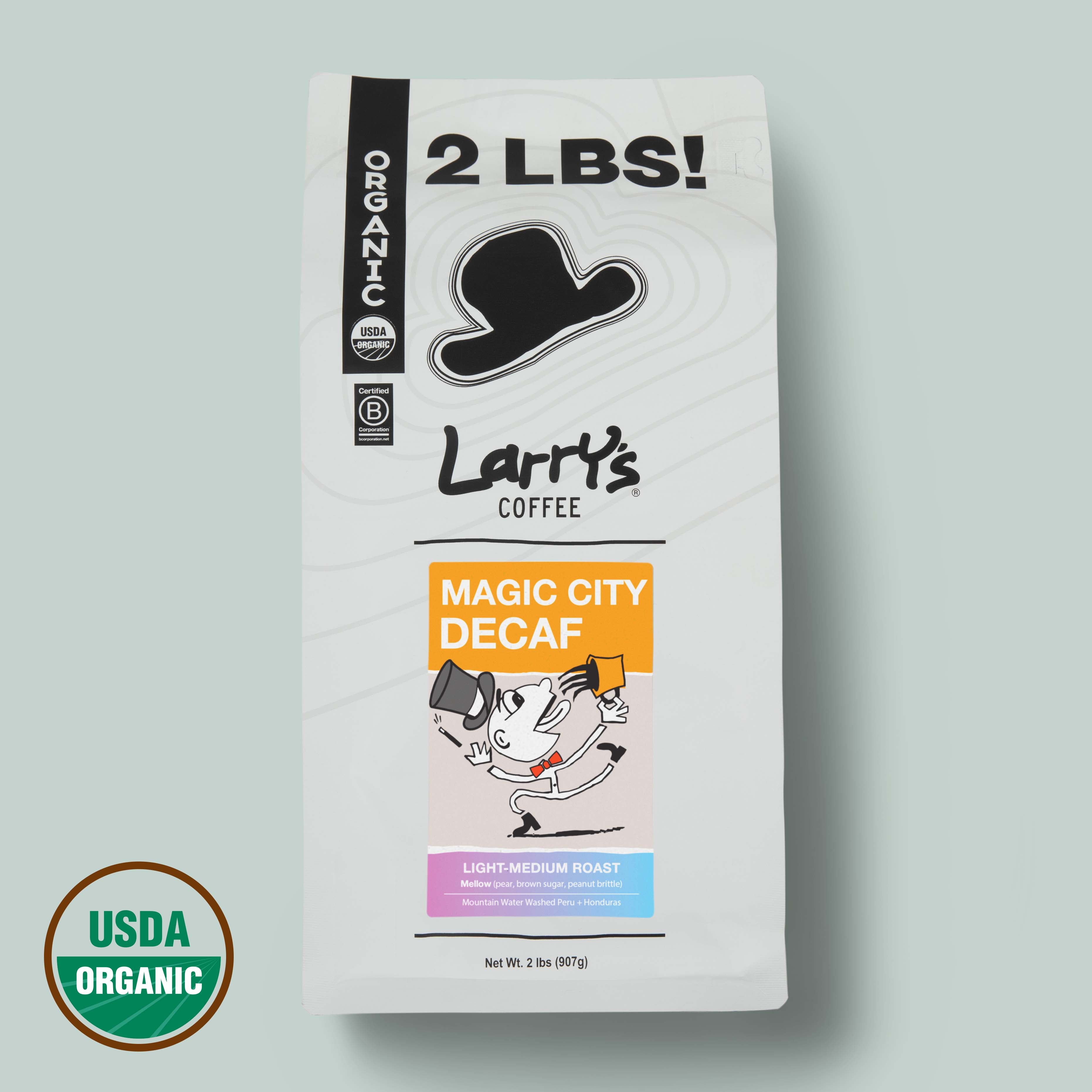 A 2 lb bag of Larry's Coffee 'Magic City Decaf' on a light sage green background, featuring a white bag with black text and graphics, a USDA Organic seal, and a black cowboy hat logo.