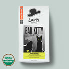 A 12 oz bag of Larry's Coffee 'Bad Kitty' Blend Dark Roast, featuring a white bag with black graphics of a hat and cat, a yellow label accent, and a USDA Organic seal in the bottom left corner, set against a solid sage green background.