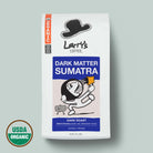 A bag of Larry's Coffee Dark Matter Sumatra dark roast coffee on a light gray background, featuring a white bag with blue and orange label blocks and a USDA Organic seal in the lower left corner.