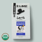 A 2 lb bag of Larry's Coffee Dark Matter Sumatra, dark roast organic coffee, shown on a light sage green background with a USDA Organic seal in the bottom-left corner.